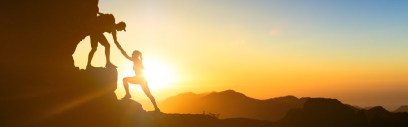 Teamwork couple helping hand trust help silhouette in mountains, sunset. Team of climbers man and woman hikers, help each other on top of mountain, climbing together, inspiring landscape on Gran Canaria